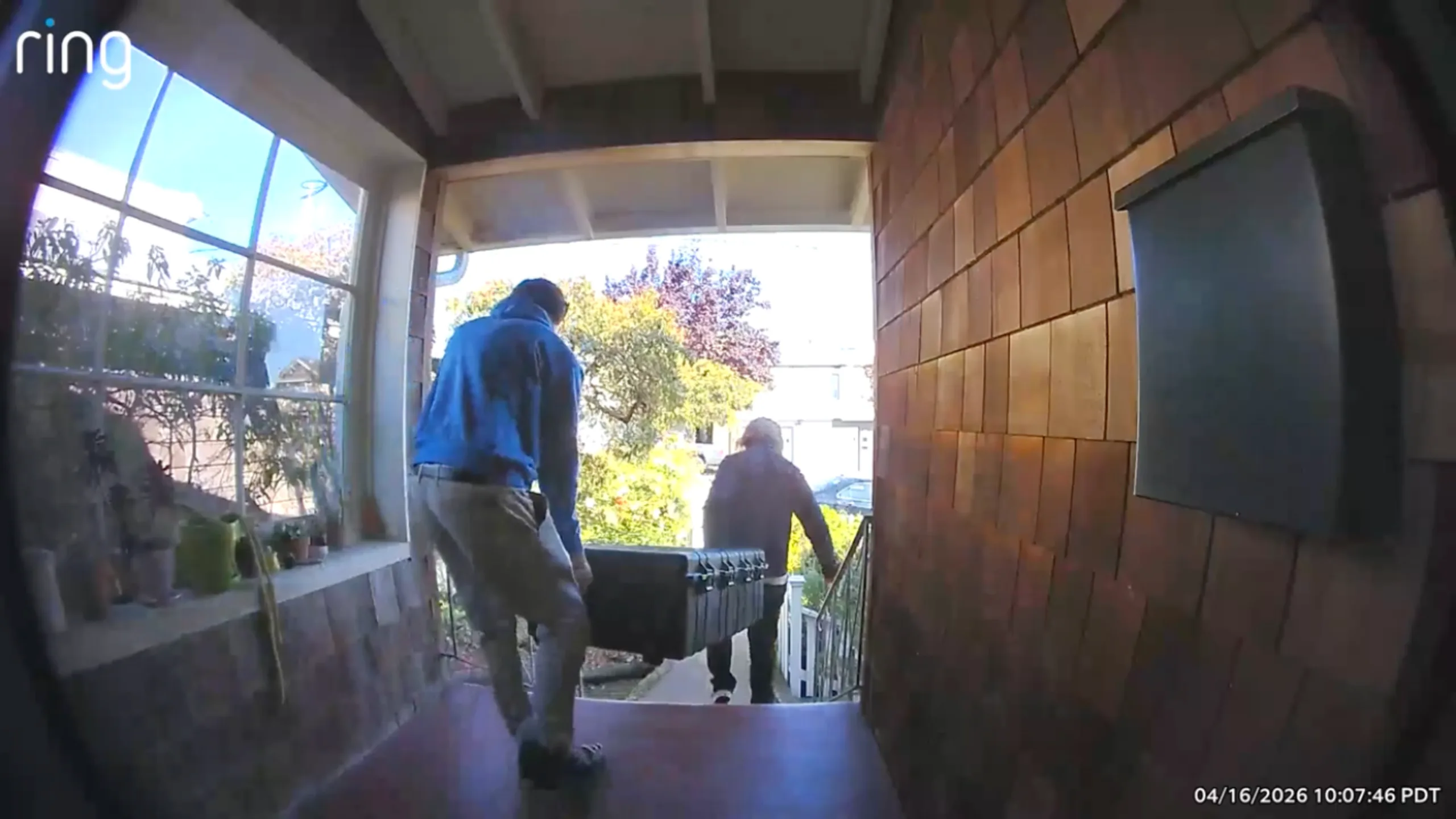 Shocking Airbnb Robot Testing Lawsuit Hits SF Startup Two people carry a large black case up the porch steps of a house, with plants on the left window sill and a mailbox on