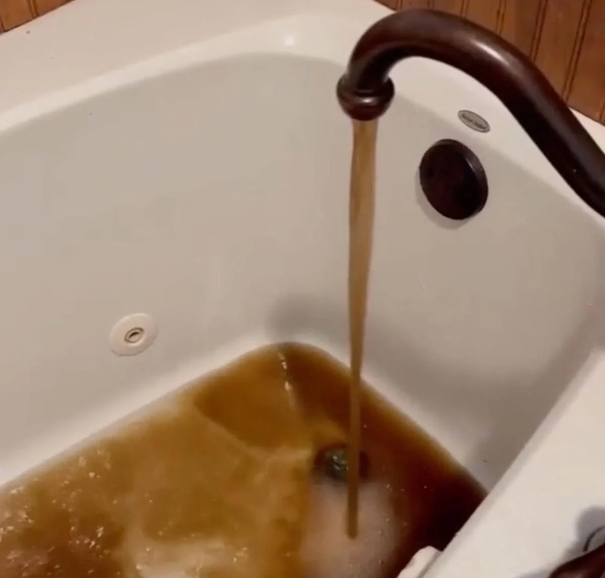 Shocking Facebook Arrest Over Texas Town's Brown Water Crisis Bathtub filling with brown, muddy-looking water flowing from a bronze faucet into a white tub.