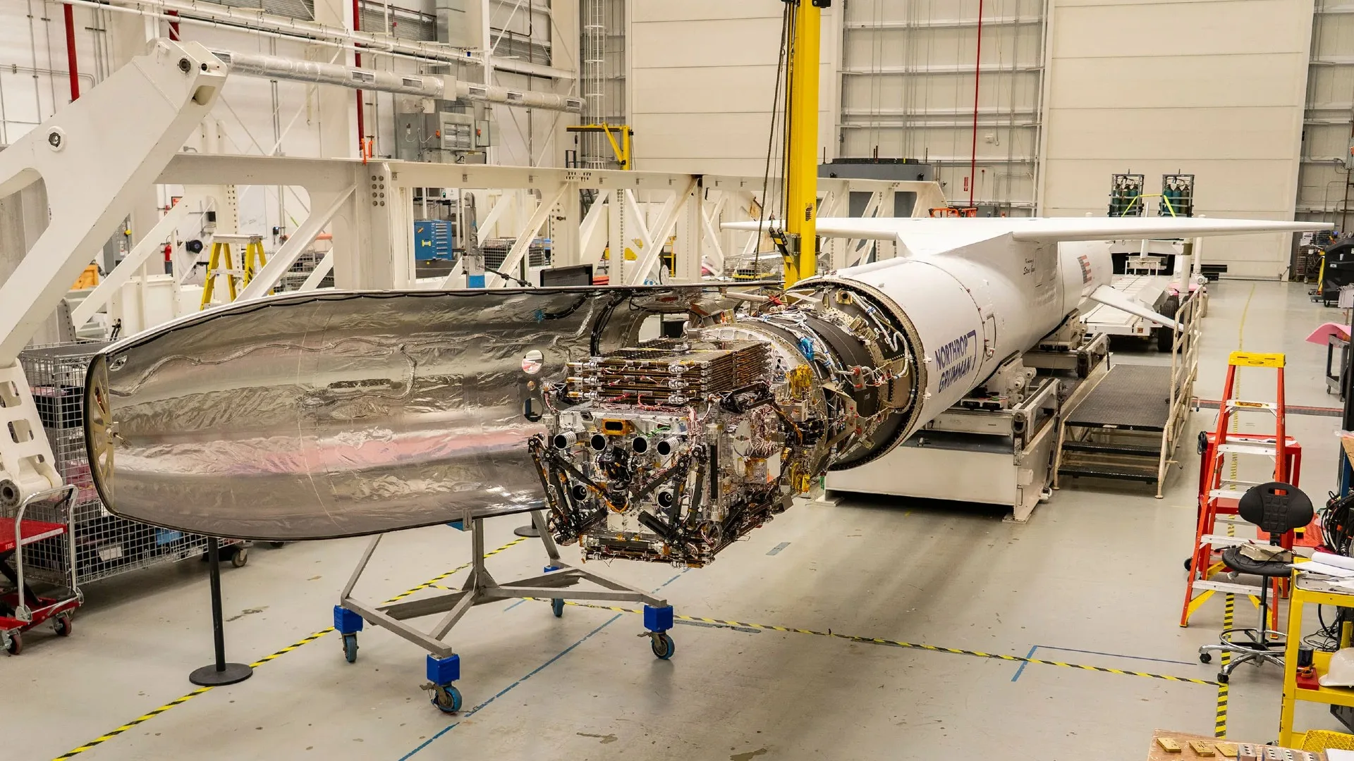 NASA's Swift Telescope Gets a New Lease on Life — Here's the Bold Plan a long white rocket sits horizontal inside a hanger with its nose cone open, exposing a satellite with many components a