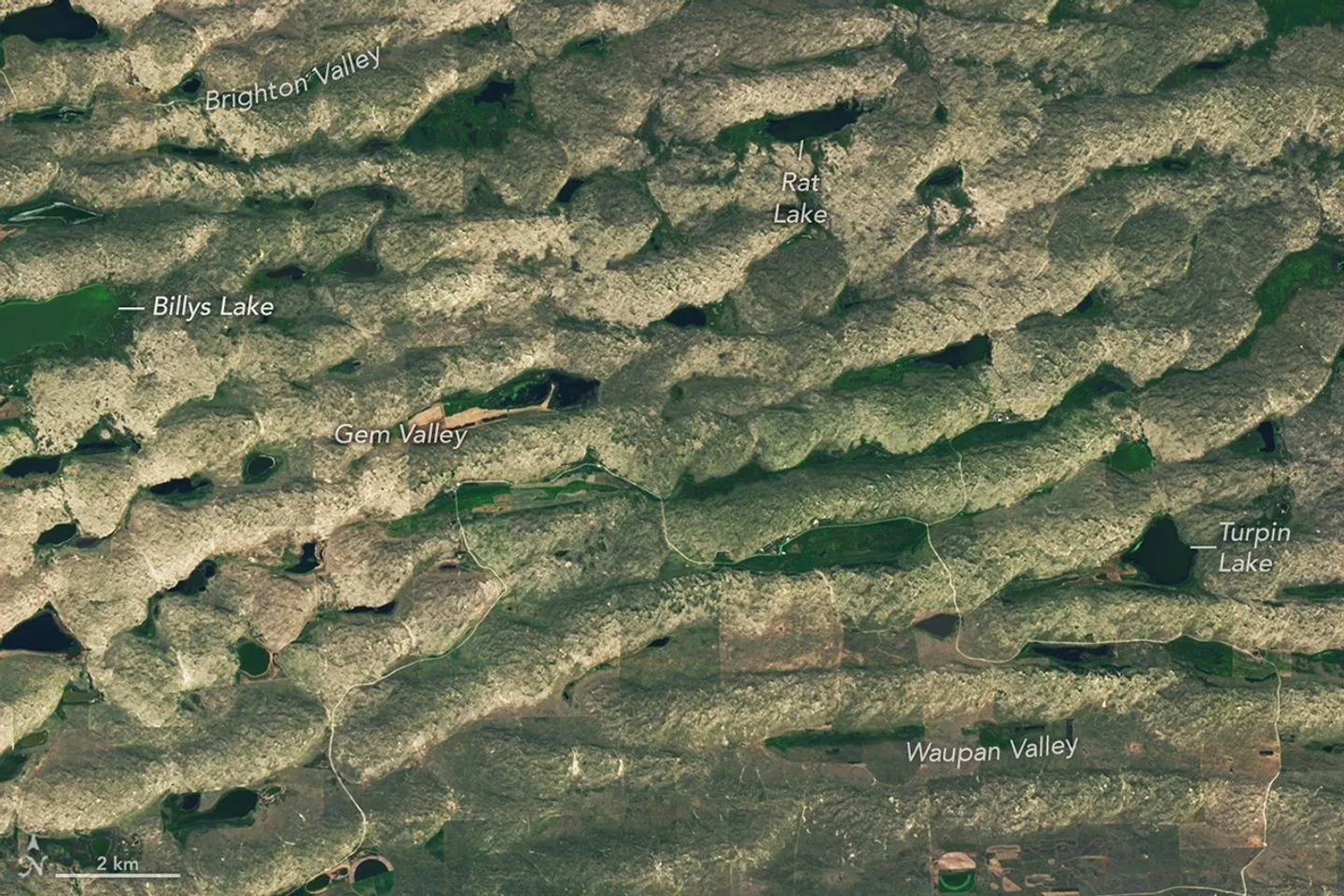 Nebraska Sandhills Explained: The Biggest Dune Field in the Western He A series of tan parallel ridges runs from left to right, with green areas and small lakes filling the low-lying spaces i