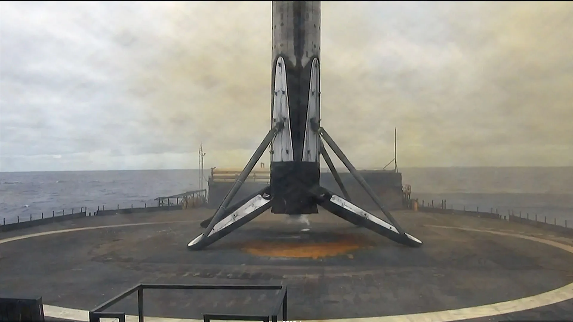 SpaceX Starlink Launch Pushes Network Past 10,700 Active Satellites Starlink satellites 2026 — the first stage of an orbital rocket stands on its four landing legs atop an ocean-based plat