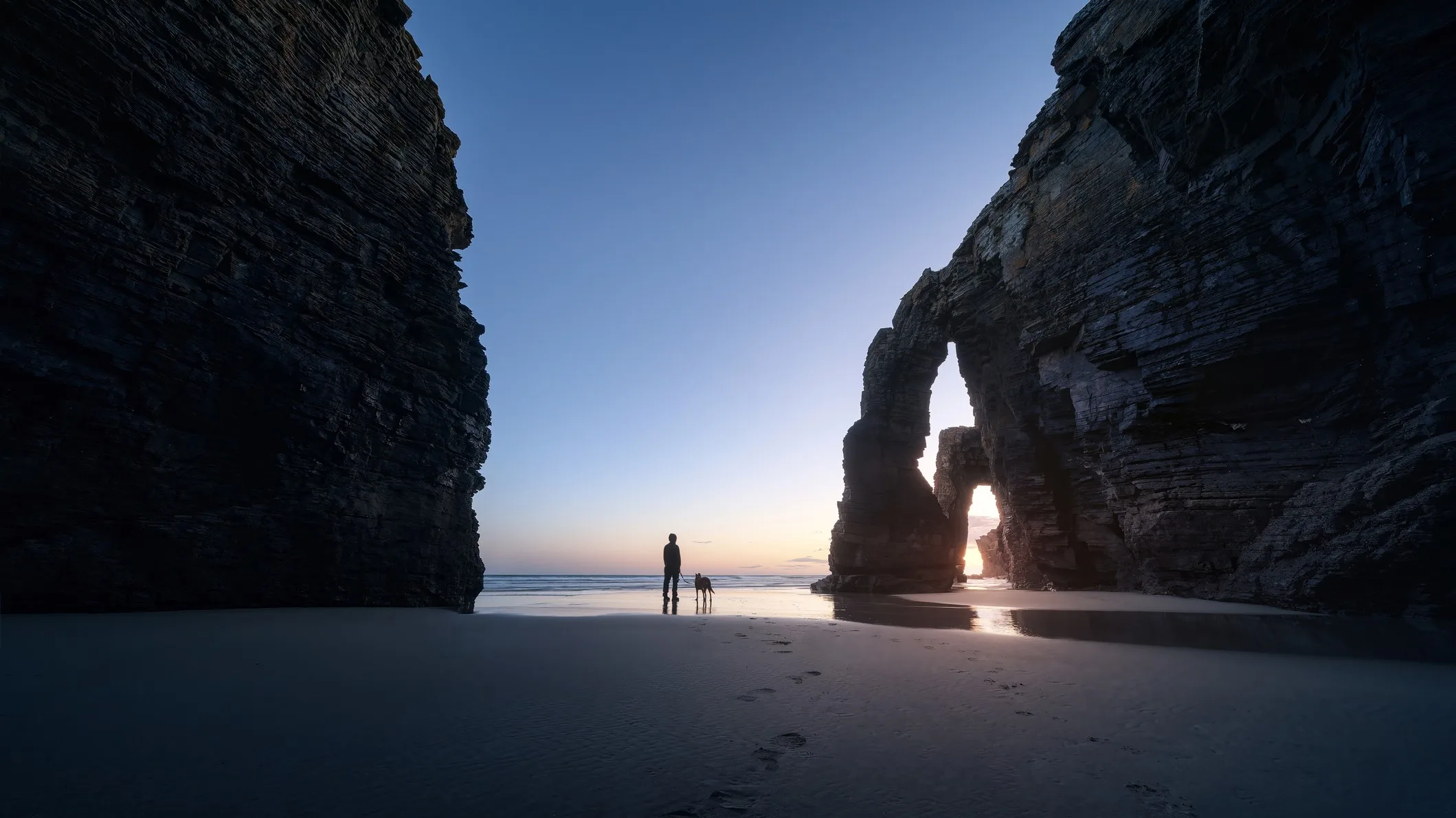 Best Spanish Beaches for the 2026 Total Solar Eclipse: 10 Top Picks 2026 total solar eclipse — stunning sunset show with vast rocky structures either side of a man and his dog looking out