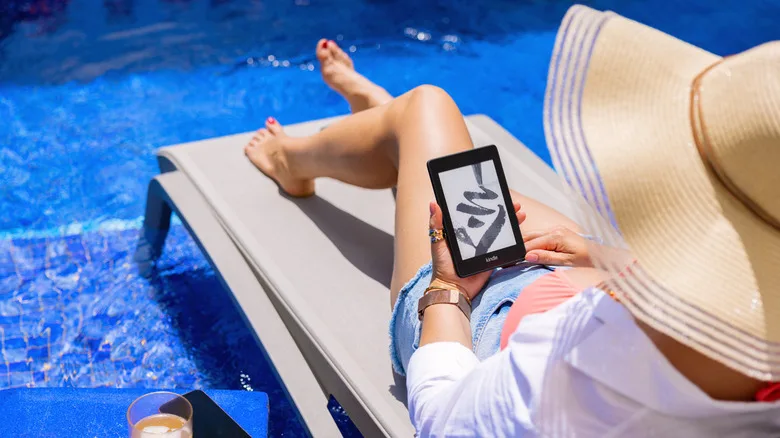 Free Kindle Books: The Best Sources You're Not Using Yet A woman in a sun hat lounges on a pool in the shallow end of a pool with a Kindle on her lap.