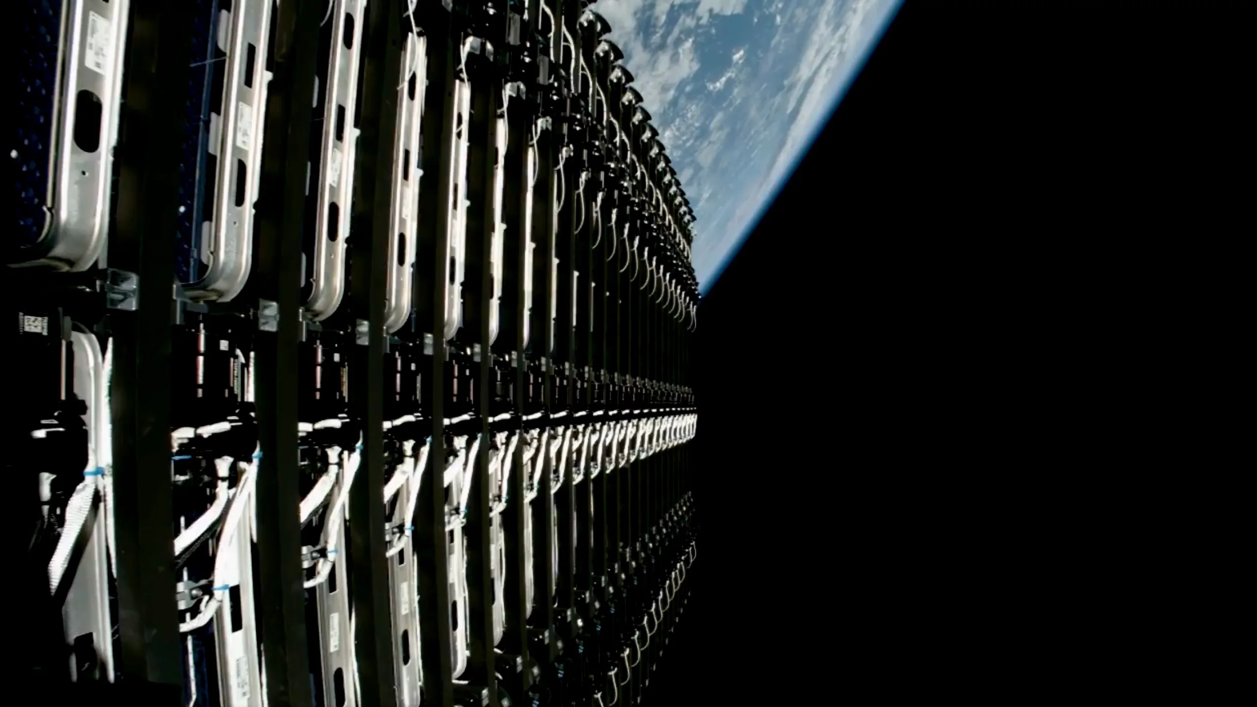 SpaceX Starlink Launch 17-54: 24 New Satellites Lift Off on IPO Week closeup view of 24 flat starlink satellites in space, before they're deployed, with earth in the background