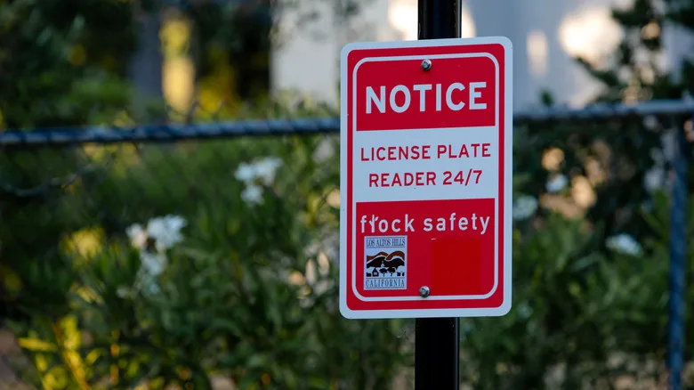 Flock Safety Cameras Track Far More Than License Plates a red and white sign for Automatic License Plate Reader (ALPR) system by Flock Safety