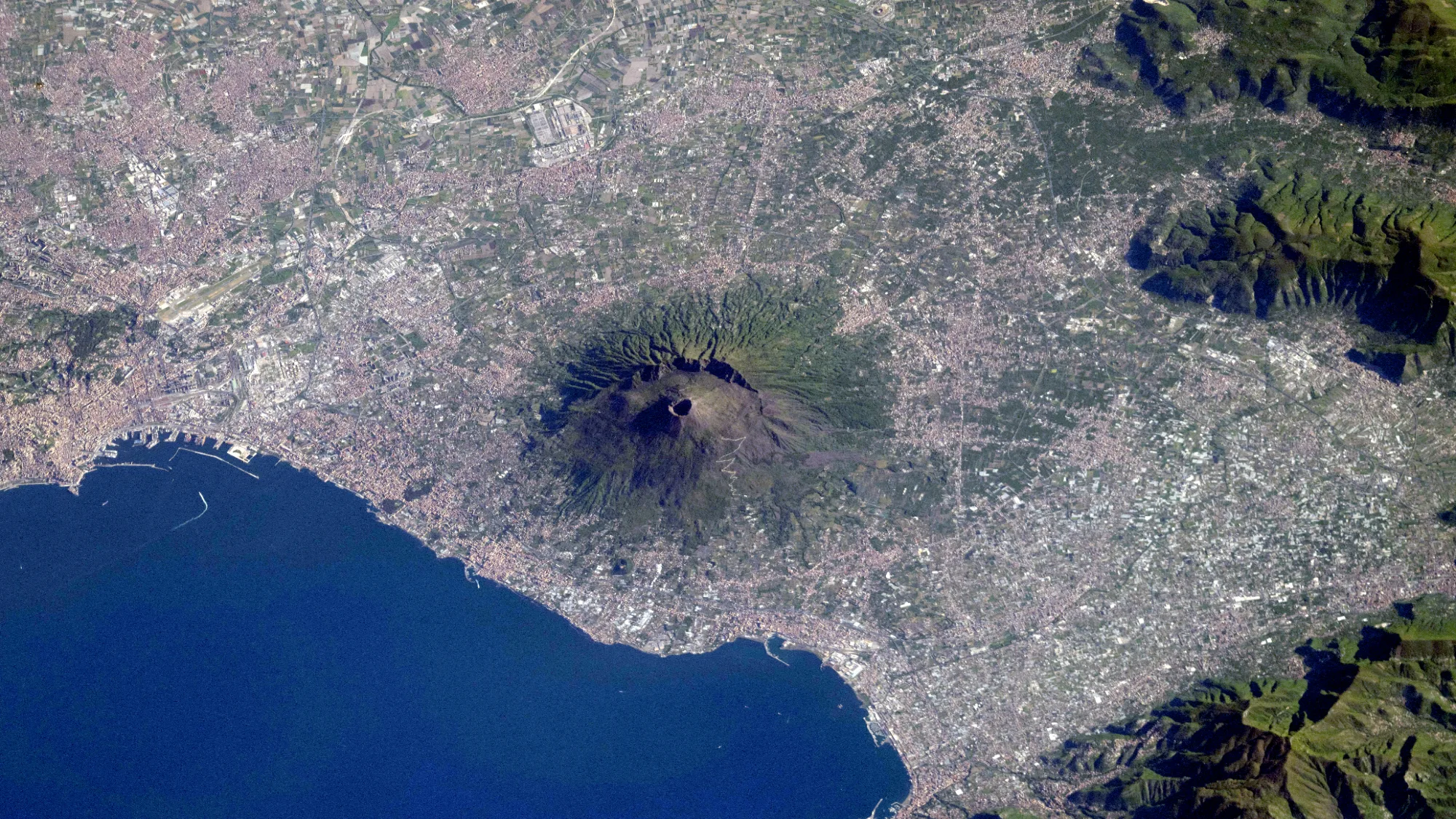 Mount Vesuvius from Space: New ISS Photo Is a Top View Mount Vesuvius from space — A large volcano stands out on the coastline nearby a body of water, as seen from above.