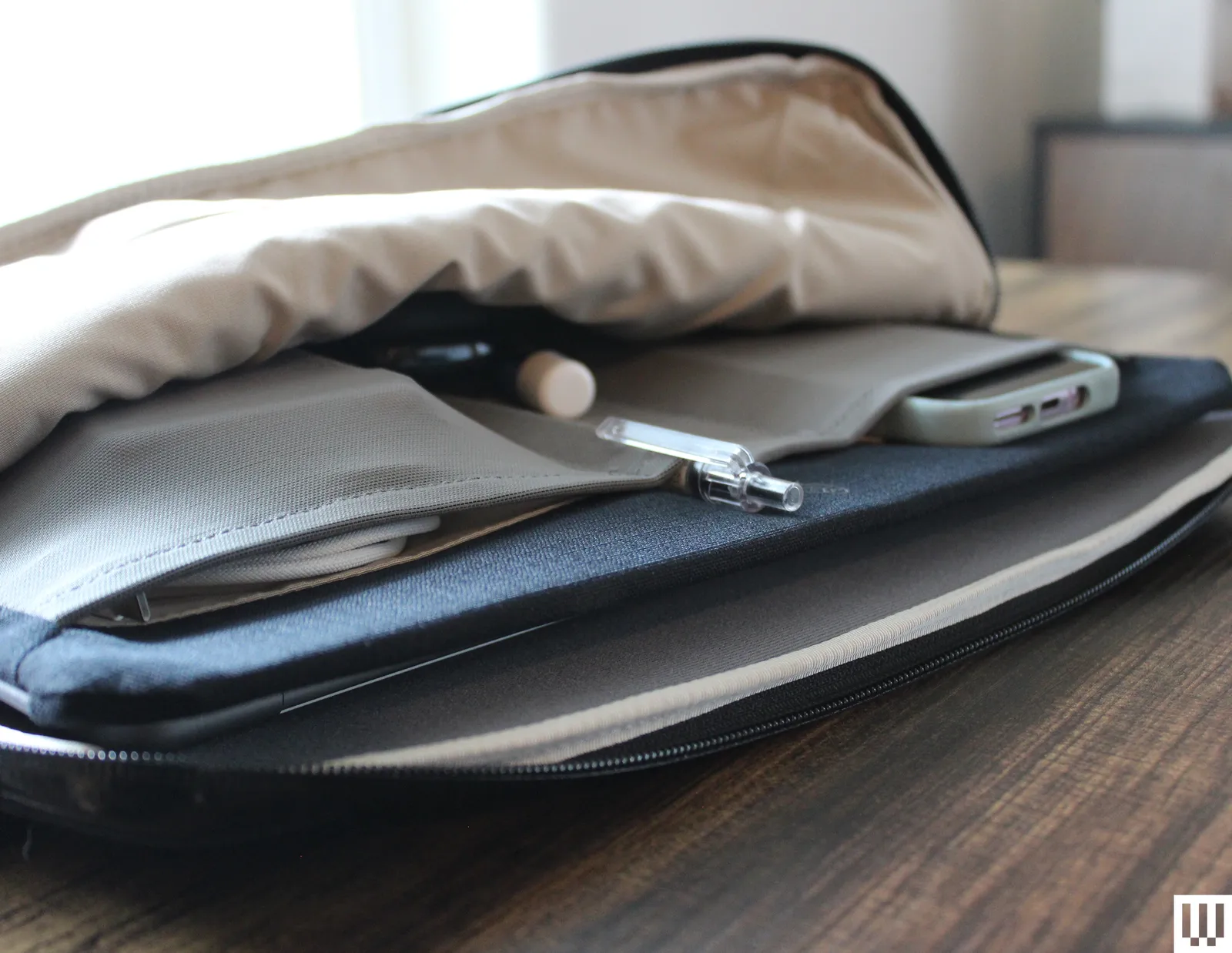 Which MacBook to Buy in 2026: Neo, Air, Pro or Wait for Ultra? A black slipcase partially open to show a laptop phone and pen inside