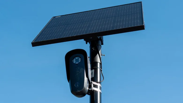 Flock Safety Cameras Track Far More Than License Plates Flock Safety cameras — Flock license plate reader and camera with solar panel against a blue sky