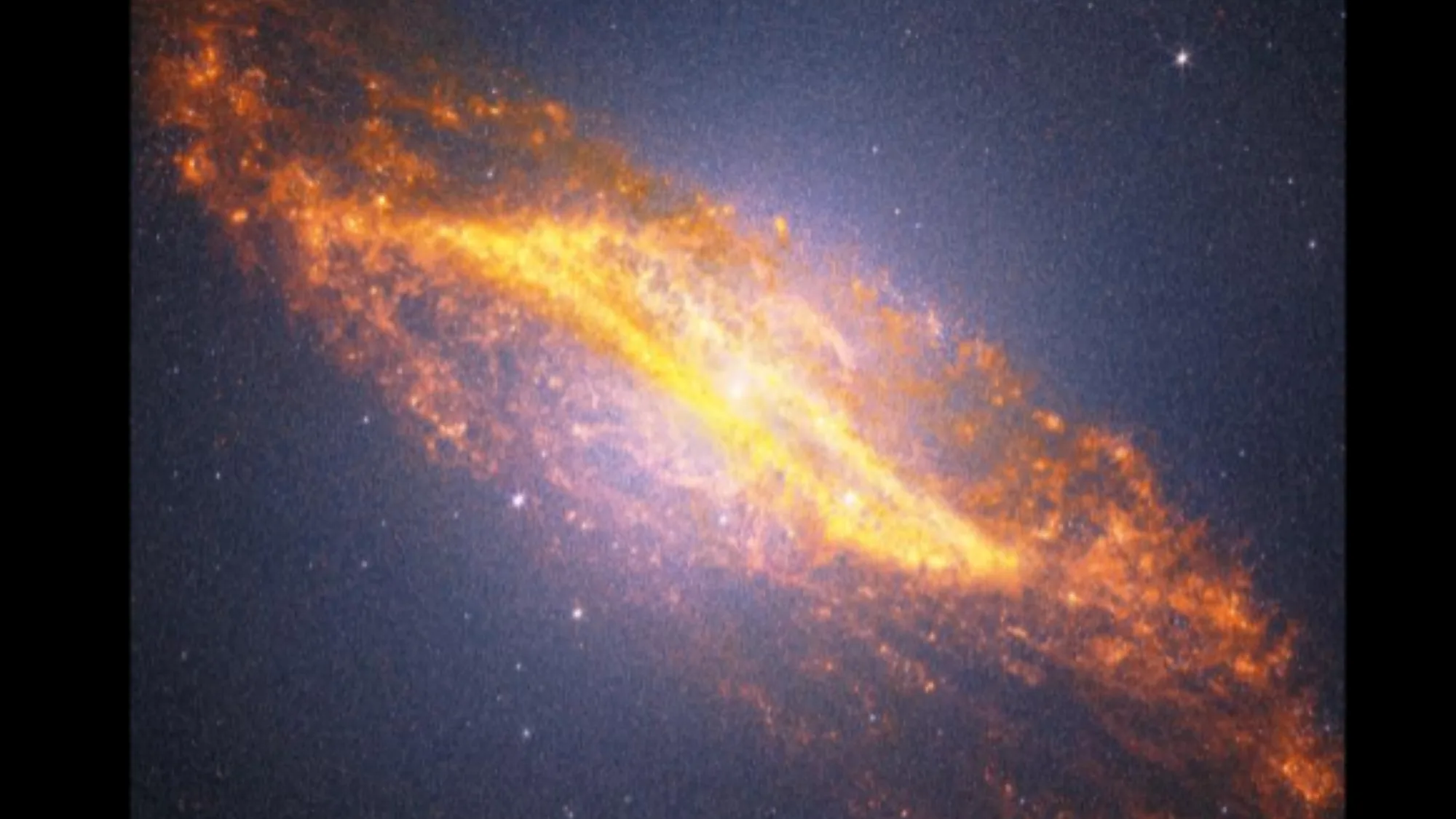 James Webb Space Telescope Turns 4 — New Images Reveal Galaxy Crash Si A blueish purple view of space with a bright yellowish structure in the center going diagonally from the top left to the