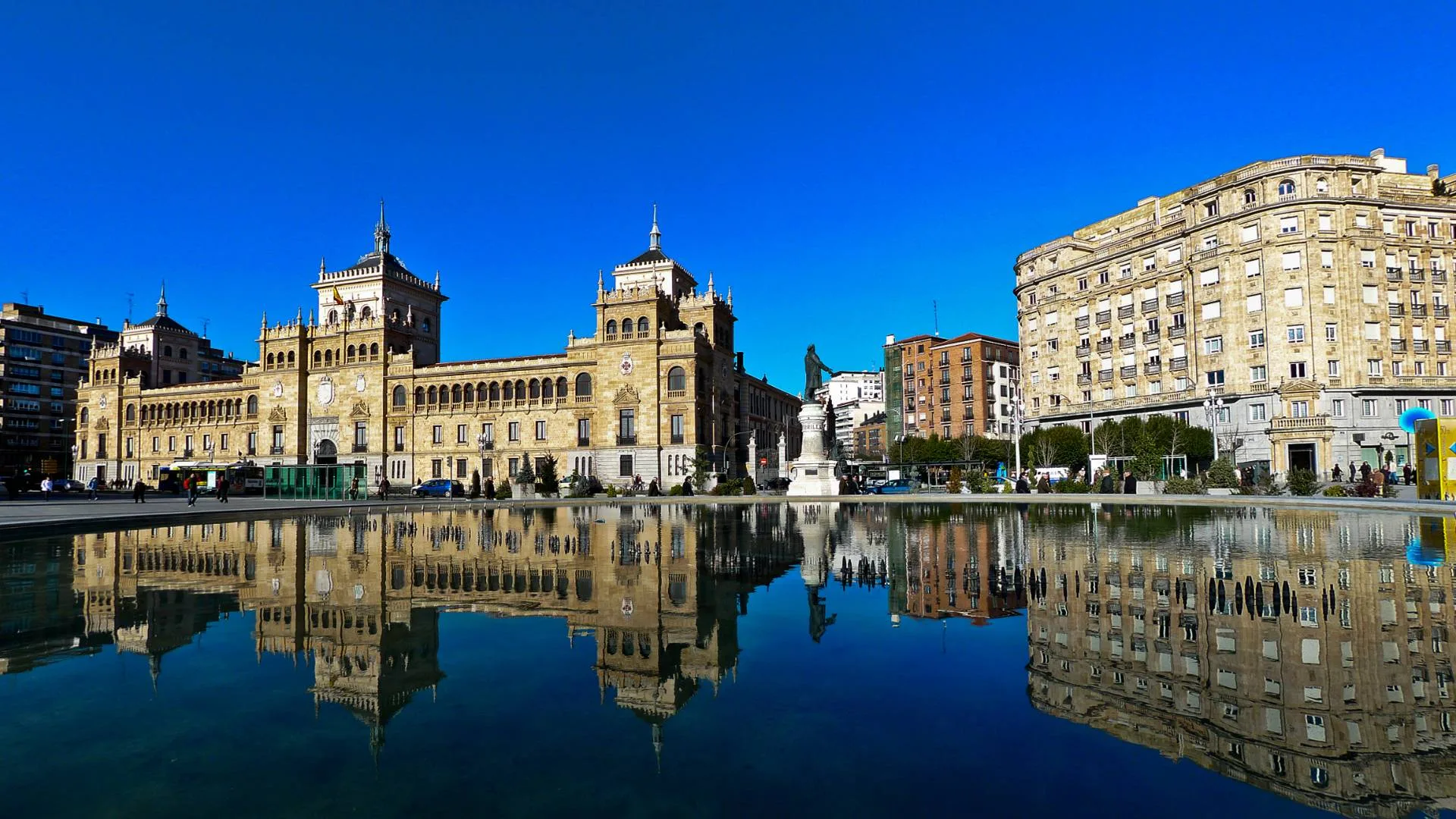 Spain Solar Eclipse 2026: Top 10 Cities for Best Views Spain solar eclipse 2026 — Large historic buildings are reflected in a big, still body of water in an urban plaza, all u