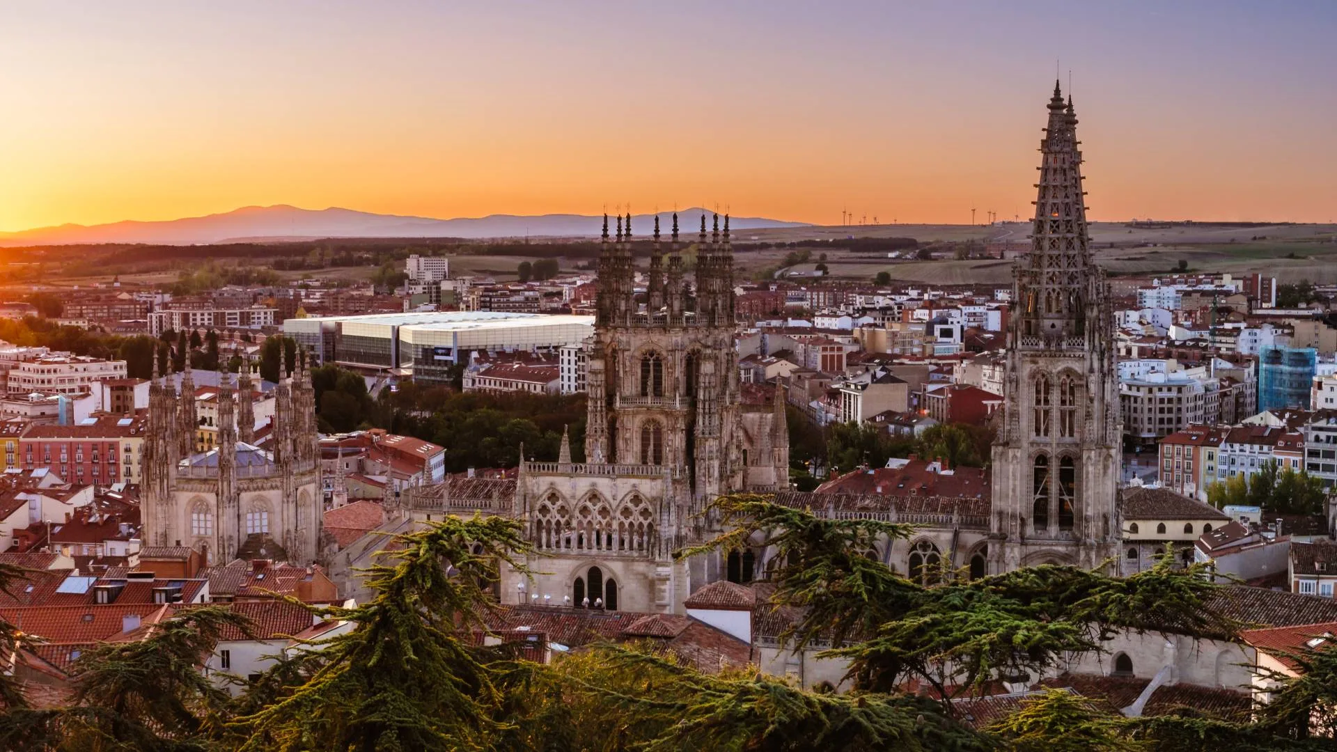 Spain Solar Eclipse 2026: Top 10 Cities for Best Views A panoramic view of a historic city at sunrise. There is a large Gothic cathedral with tall spires in the foreground and