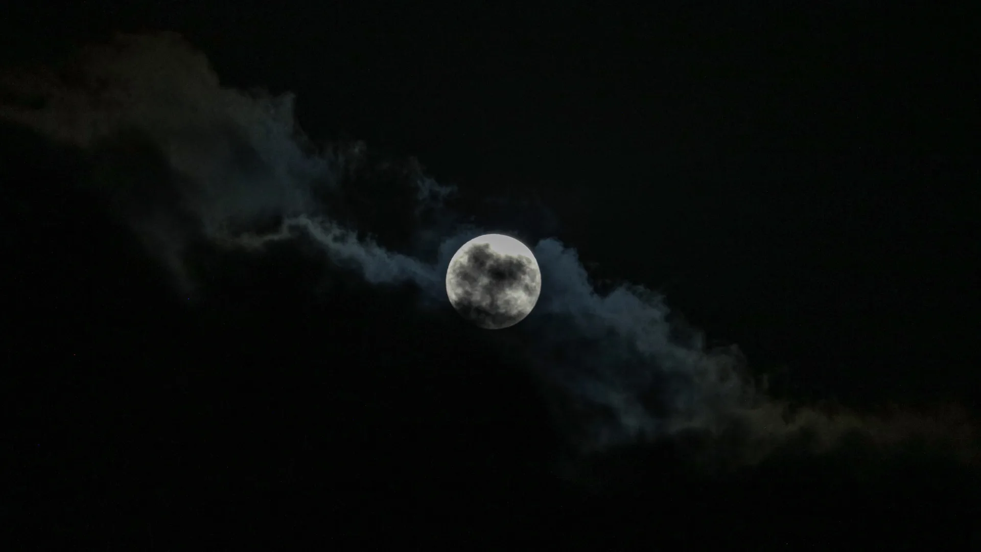July 2026 Buck Moon: Your Complete Guide to Seeing It A silver full moon glows in a dark sky behind a bank of encroaching cloud.