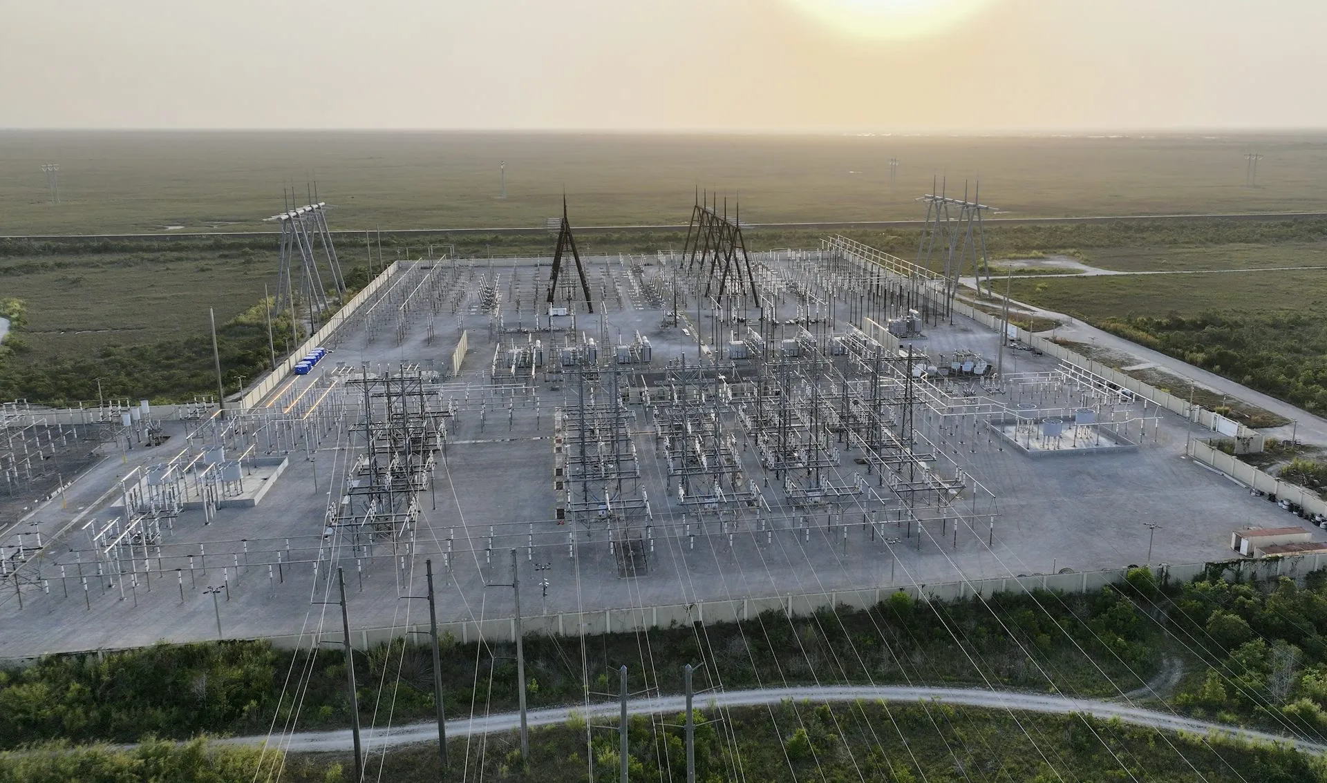 Data Center Electricity Is Adding $23B to Power Bills data center electricity — An aerial view of an area covered in wires, metal boxes and towers.