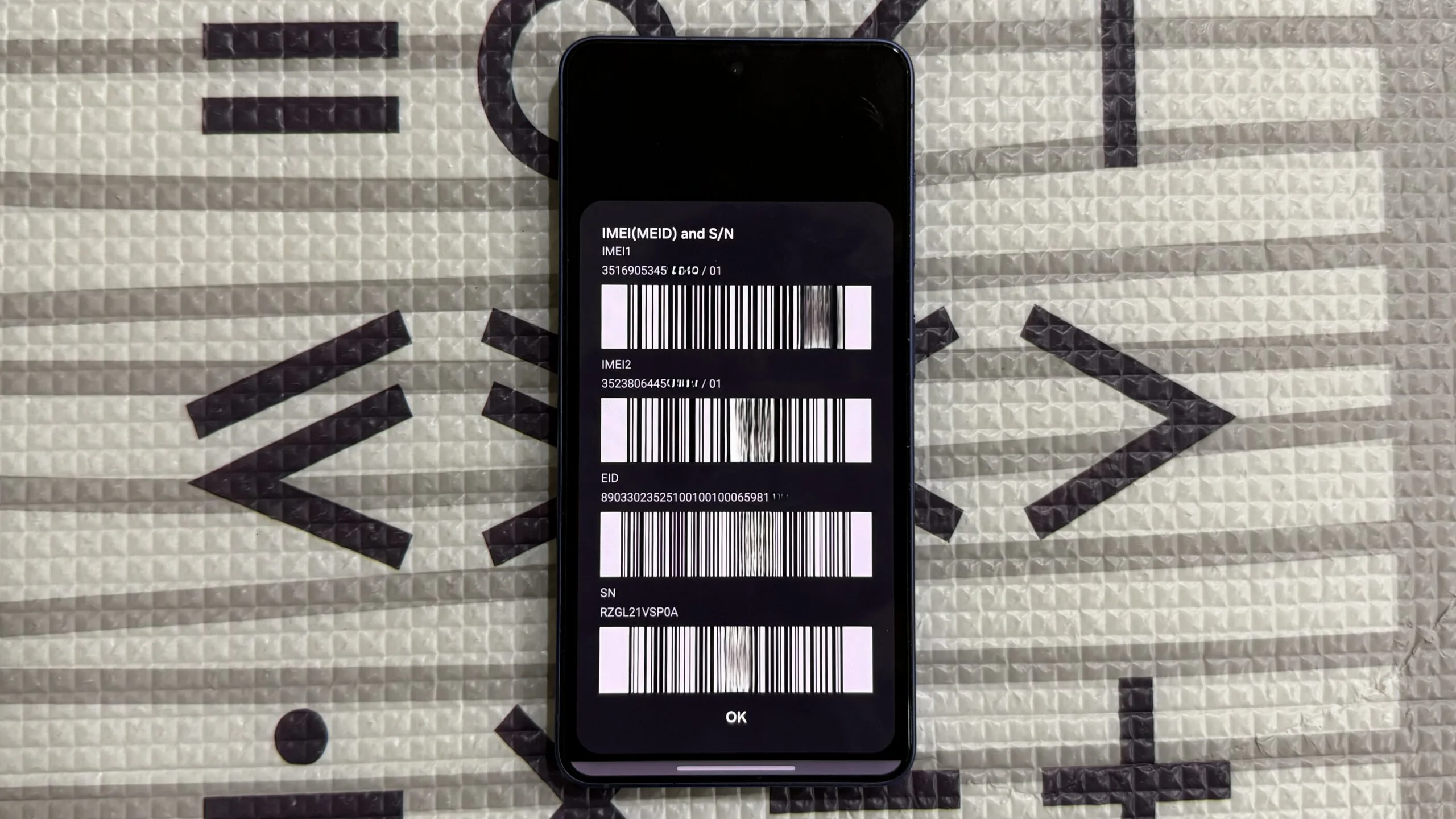 6 Samsung Dial Codes That Unlock Expert Hidden Features Samsung phone on a mat showing IMEI numbers