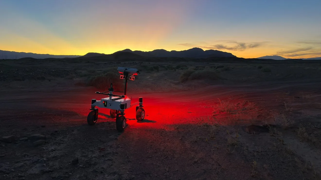 NASA's ERNEST Mars Rover Prototype Is the Smartest One Yet Mars rover prototype — a small, four-wheeled rover shines a red light on a dark desert ground and the sun sets behind si