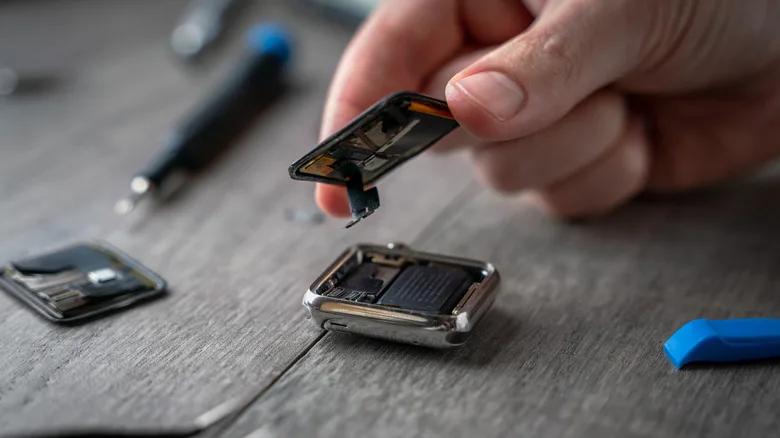 Apple Watch Battery Replacement: The $99 Decision Explained A person removing the case from an Apple Watch using a kit to replace the battery.