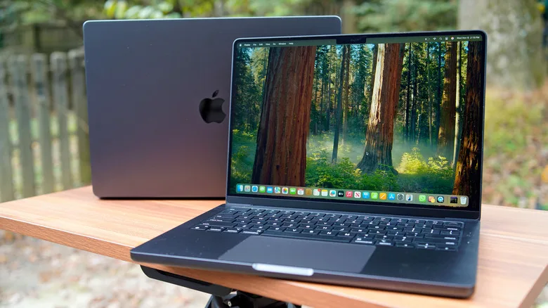 MacBook Pro Prices: The Critical $500 Shift Since 2021 An outdoor shot of two MacBook Pros sitting back-to-back on a table.